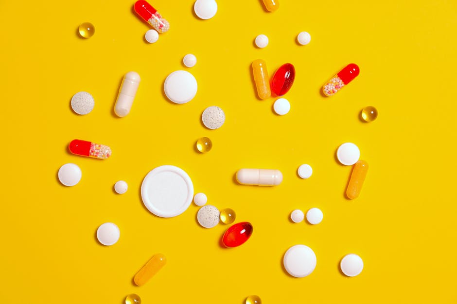 a variety of pills and capsules scattered on a vibrant yello