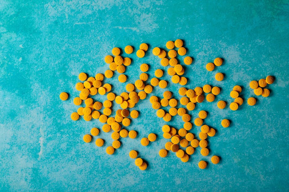 close up of scattered yellow pills on a vibrant turquoise ba